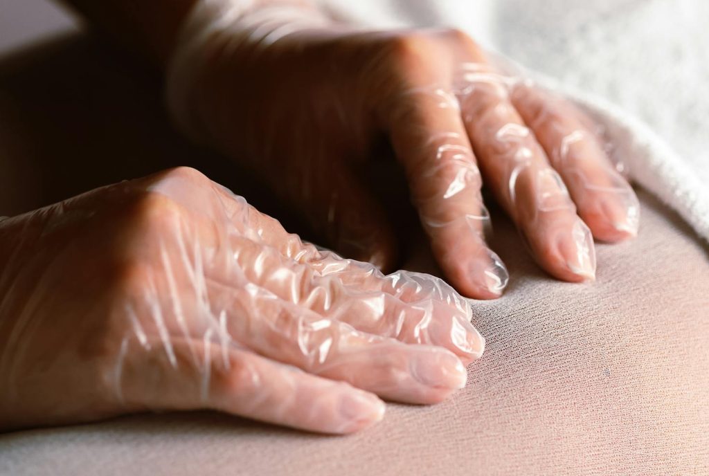 A relaxing massage therapy session using protective gloves on a client's leg.